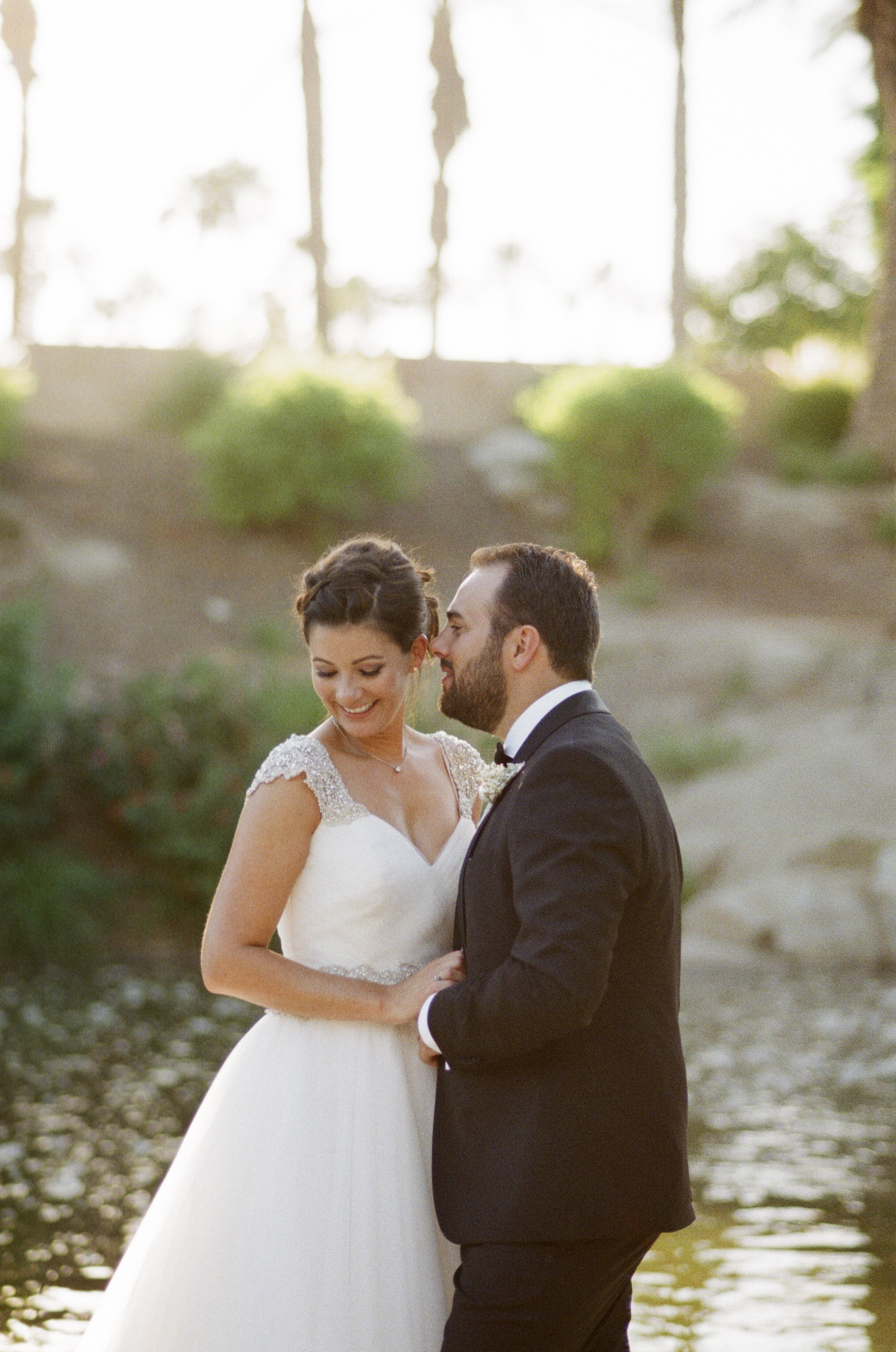 Bride and groom beside a creek at Indian Wells Golf Resort