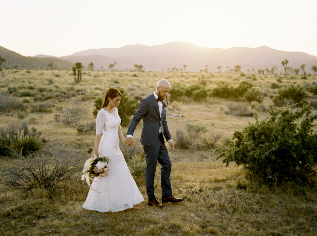 bride and groom walk hand in hand in the Palm Spring desert during their micro wedding