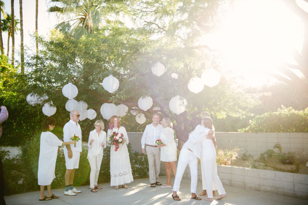 wedding ceremony with everyone dressed in white with sun flare