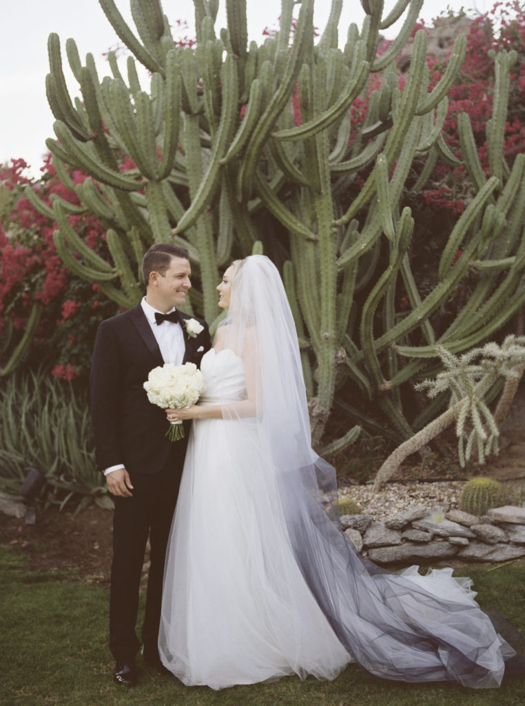 Bride and groom portrait in front of bougainvillea and cactus garden right after their ceremony. Image was shot on Kodak film. 