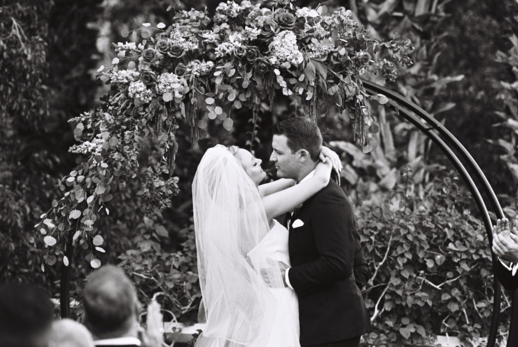 Black and white film image of bride and groom right after their first kiss during the ceremony. 