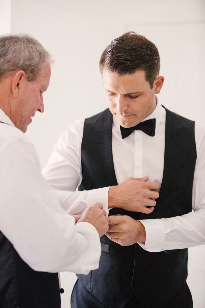 Father of the groom putting cufflinks on his son on his wedding day
