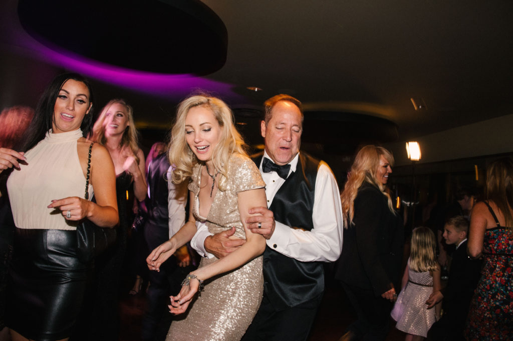 Bride dances with her father on the dance floor as a party commences during the wedding reception
