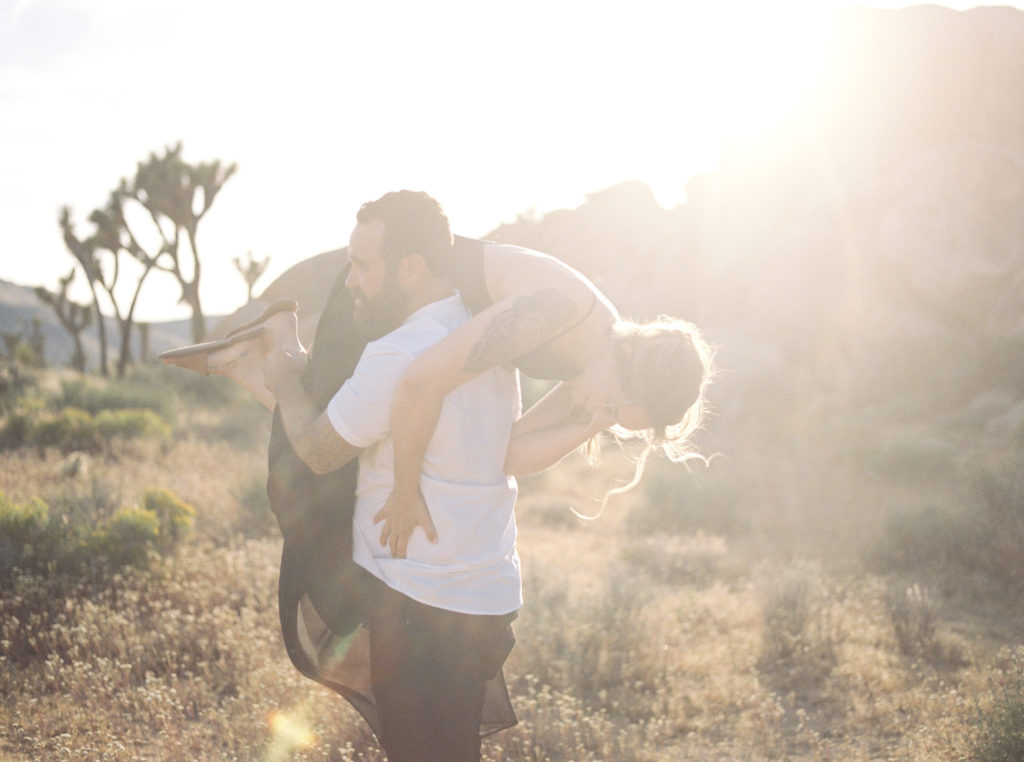 groom carrying bride away in for their joshua tree engagement