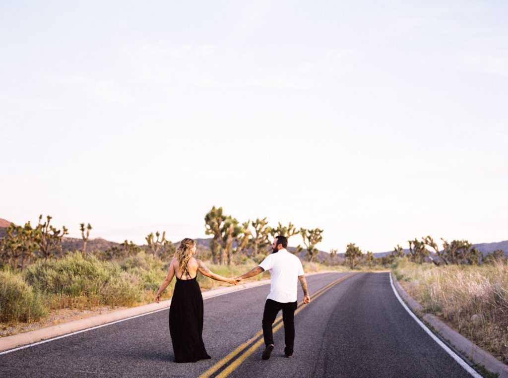 bride and groom walking down the street for their joshua tree engagement 