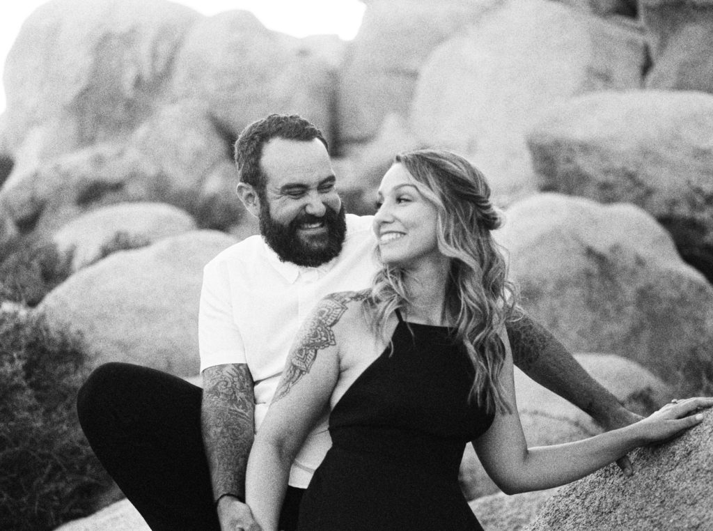 bride and groom laughing in boulders in black and white film for their Joshua Tree engagement