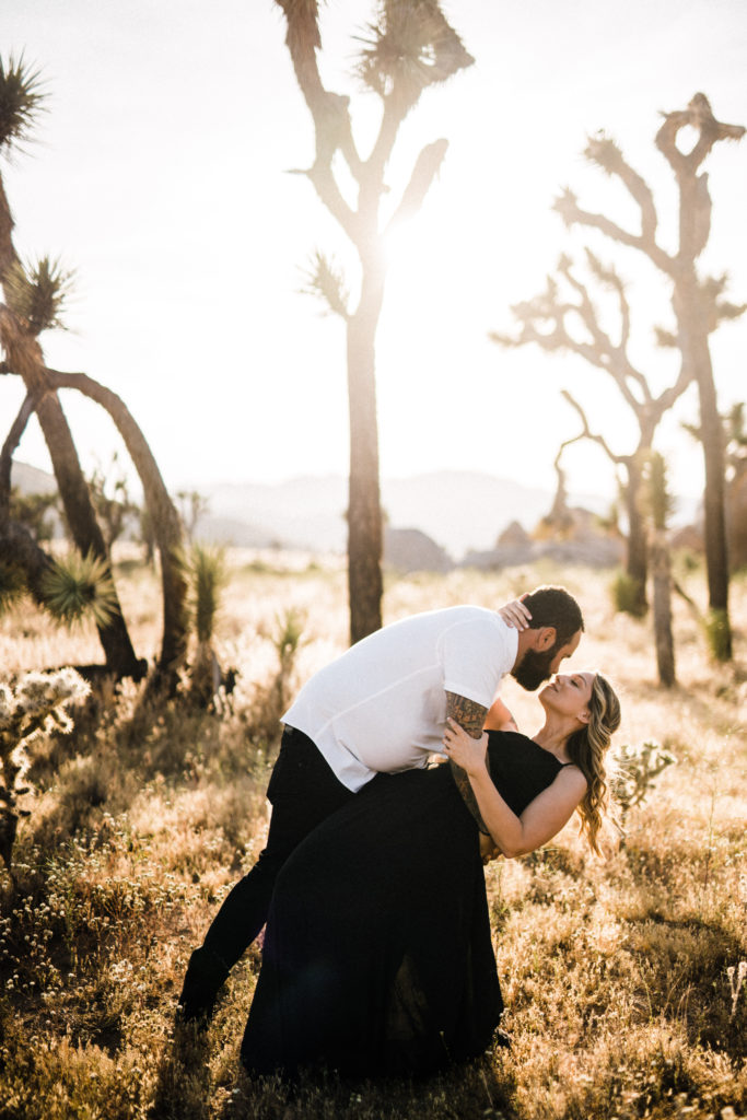 groom dipping bride in joshua tree for their engagement photos
