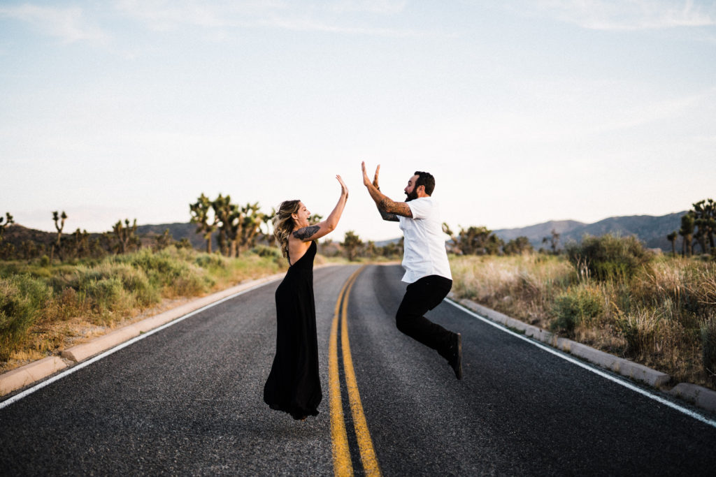bride and groom jumping in the air for their joshua tree engagement 