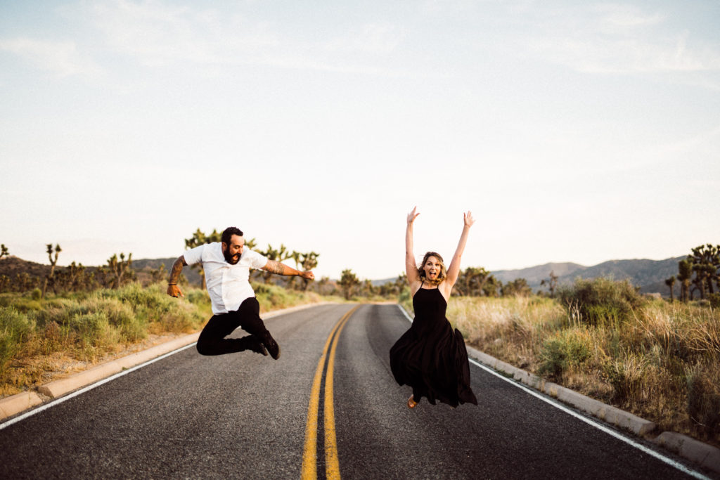 bride and groom jumping in the air for their joshua tree engagement