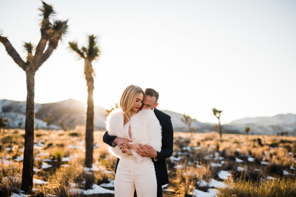 bride and groom embracing with snowfall during their micro wedding in joshua tree