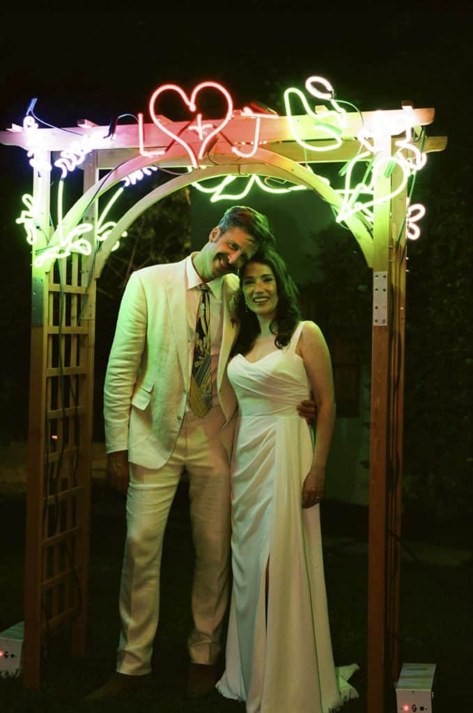 bride and groom under neon light arch
